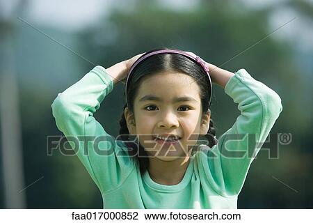 Girl with hands on head, smiling at camera View Large Photo Image Stock Image - Girl with hands on head, smiling at camera. Fotosearch