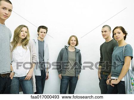 Stock Image - Group of young adult and teenage friends, looking at camera, three quarter length, white background. Fotosearch