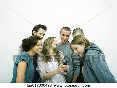 Stock Photo - Group of young adult and teenage friends looking at cell phone, white background. Fotosearch
