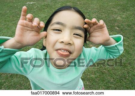 Picture - Little girl sticking out tongue at camera. Fotosearch