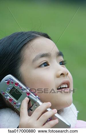 Stock Image - Little girl using cell phone, close-up. Fotosearch