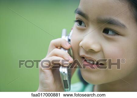 Stock Image - Little girl using cell phone, close-up. Fotosearch