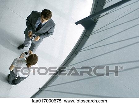 Stock Photography - Male and female associates having coffee, full length, high angle view. Fotosearch
