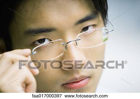 Man adjusting glasses, looking at camera, close-up View Large Photo Image Stock Photo - Man adjusting glasses, looking at camera, close-up. Fotosearch