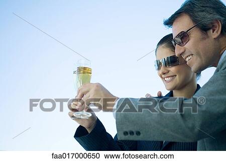 Man and woman clinking glasses of champagne, sky in background View Large Photo Image Stock Image - Man and woman clinking glasses of champagne, sky in background. Fotosearch