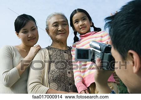 Picture - Man filming family with video camera. Fotosearch