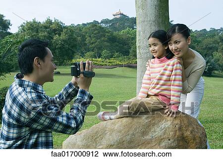 Man filming wife and daughter in park with video camera View Large Photo Image Stock Image - Man filming wife and daughter in park with video camera. Fotosearch