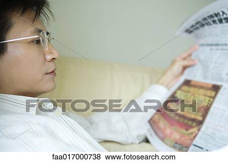Stock Photo - Man reading newspaper, side view. Fotosearch