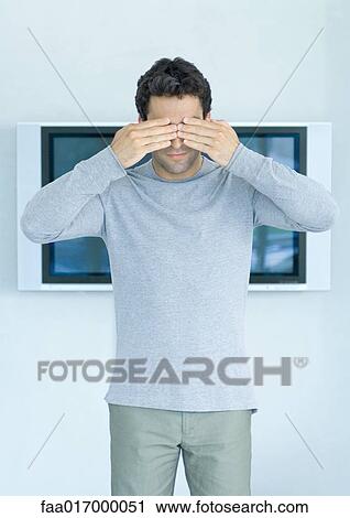 Man standing in front of wide screen TV, hands over eyes View Large Photo Image Stock Image - Man standing in front of wide screen TV, hands over eyes. Fotosearch