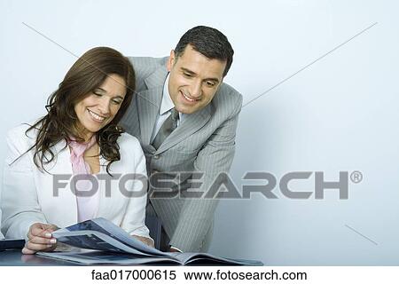 Stock Photography - Mature business colleagues looking at magazine together. Fotosearch
