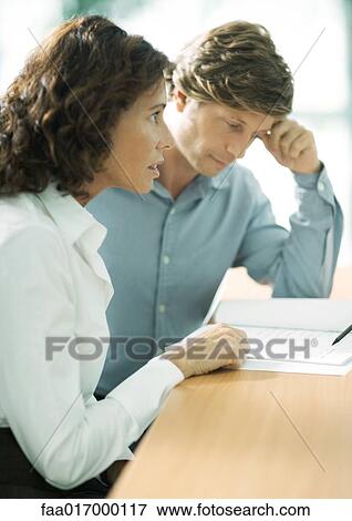 Mature couple sitting at table, man looking down at document, woman looking out of frame View Large Photo Image Stock Photo - Mature couple sitting at table, man looking down at document, woman looking out of frame. Fotosearch