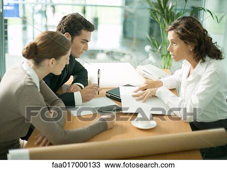 Stock Image - Mature female architect speaking to clients. Fotosearch