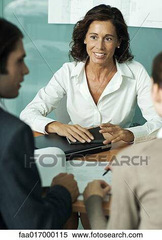 Mature female professional sitting across from clients, smiling View Large Photo Image Stock Photography - Mature female professional sitting across from clients, smiling. Fotosearch