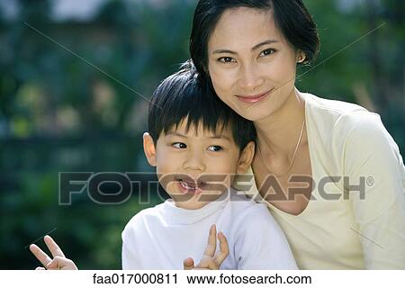 Stock Image - Mother and son, boy making "v" signs with fingers, portrait. Fotosearch