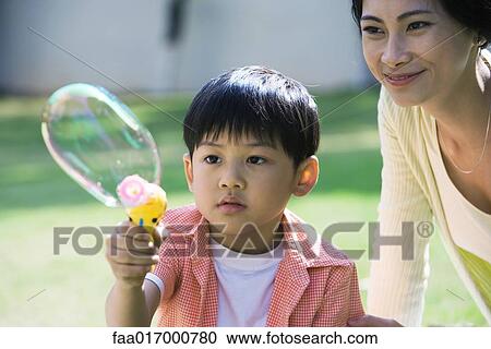 Mother and son making bubbles View Large Photo Image Stock Image - Mother and son making bubbles. Fotosearch