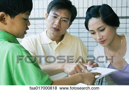 Parents and son looking at book together View Large Photo Image Stock Photo - Parents and son looking at book together. Fotosearch