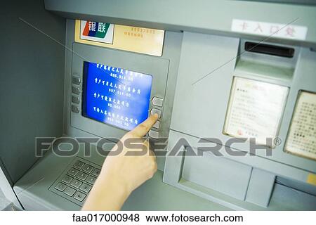 Stock Photo - Person using ATM machine, cropped view. Fotosearch