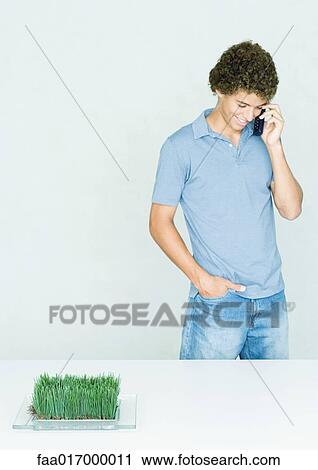 Stock Image - Teenage boy standing, using cell phone. Fotosearch