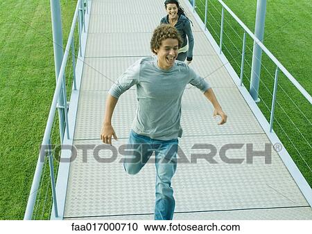Teenage couple running on walkway View Large Photo Image Stock Image - Teenage couple running on walkway. Fotosearch