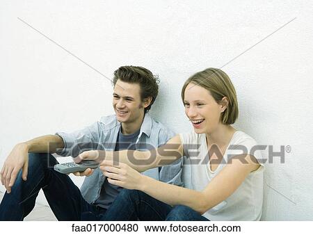 Teenage girl and young man sitting on floor, girl pointing remote control out of frame View Large Photo Image Stock Image - Teenage girl and young man sitting on floor, girl pointing remote control out of frame. Fotosearch