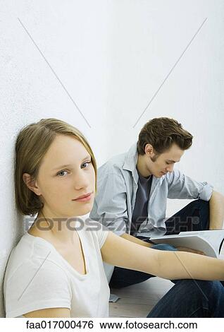 Teenage girl and young man sitting on floor, girl looking at camera View Large Photo Image Stock Photograph - Teenage girl and young man sitting on floor, girl looking at camera. Fotosearch