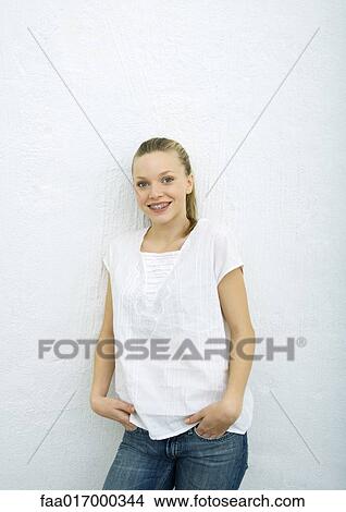 Picture - Teenage girl leaning against wall, smiling at camera, portrait. Fotosearch