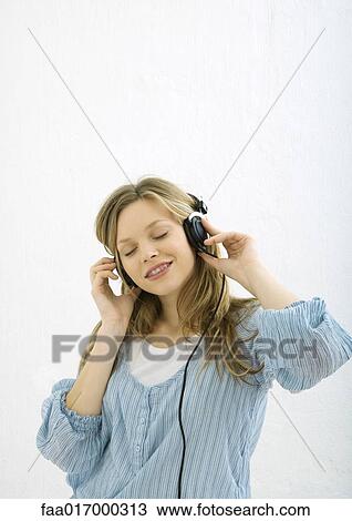 Stock Image - Teenage girl listening to headphones, portrait. Fotosearch
