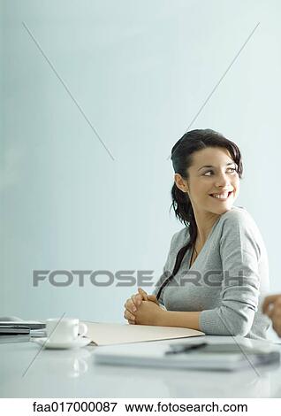 Stock Photo - Teenage girl sitting at table with file and coffee cup, smiling over shoulder. Fotosearch