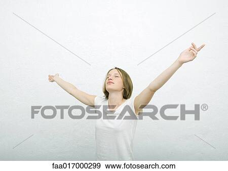 Stock Photo - Teenage girl standing with arms out and eyes closed, portrait. Fotosearch