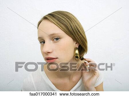 Stock Image - Teenage girl wearing earring looking at camera . Fotosearch