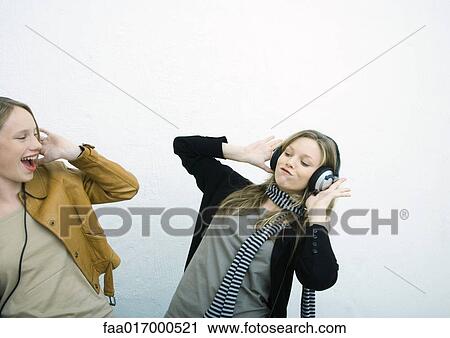 Stock Image - Teenage girls listening to headphones. Fotosearch