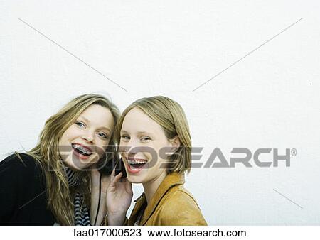 Stock Image - Teenage girls sharing headphones. Fotosearch