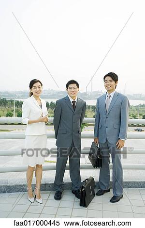 Three business executives standing by railing, looking at camera, full length portrait View Large Photo Image Stock Photography - Three business executives standing by railing, looking at camera, full length portrait. Fotosearch
