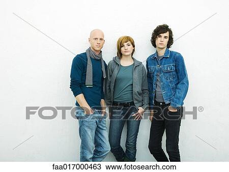 Three young adults leaning against wall, looking at camera, portrait, white background View Large Photo Image Stock Image - Three young adults leaning against wall, looking at camera, portrait, white background. Fotosearch