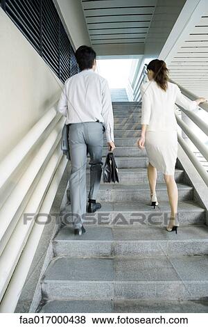 Stock Photo - Two business executives walking up stairs, low angle view. Fotosearch