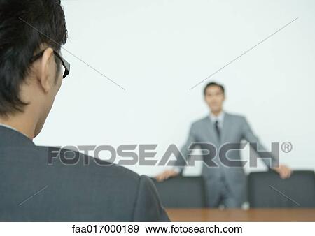 Two businessmen facing each other across conference table View Large Photo Image Stock Photo - Two businessmen facing each other across conference table. Fotosearch