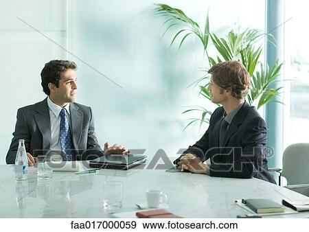 Two businessmen sitting at table, having meeting View Large Photo Image Stock Photo - Two businessmen sitting at table, having meeting. Fotosearch