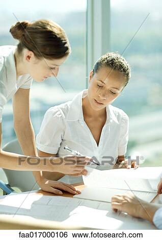 Stock Photograph - Two women discussing document together. Fotosearch
