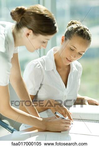 Stock Photography - Two women discussing document together. Fotosearch