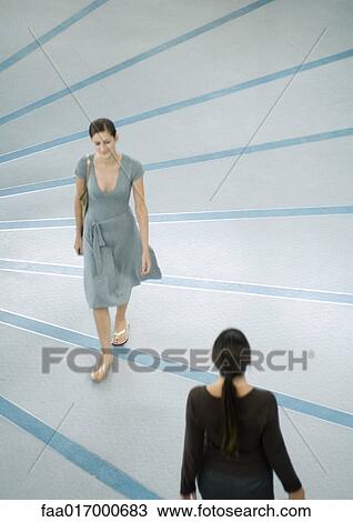 Two women walking by each other View Large Photo Image Stock Image - Two women walking by each other. Fotosearch