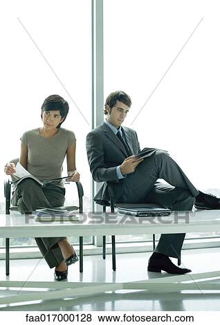 Stock Photo - Two young professional adults sitting in waiting room. Fotosearch