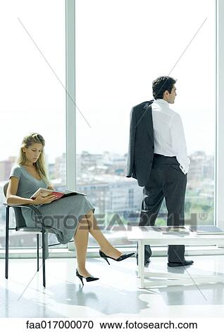 Waiting room, woman sitting reading magazine while man looks out window View Large Photo Image Stock Image - Waiting room, woman sitting reading magazine while man looks out window. Fotosearch