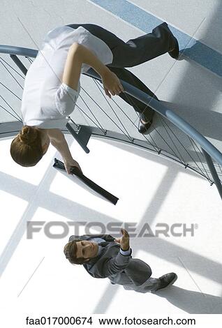 Woman leaning over railing, handing man briefcase View Large Photo Image Picture - Woman leaning over railing, handing man briefcase. Fotosearch
