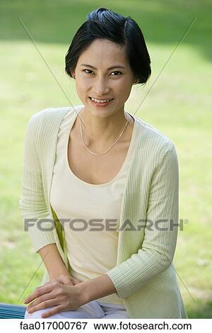 Woman sitting outdoors, smiling at camera, portrait View Large Photo Image Stock Photo - Woman sitting outdoors, smiling at camera, portrait. Fotosearch