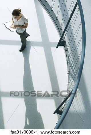 Woman standing with book, walking, high angle view View Large Photo Image Stock Image - Woman standing with book, walking, high angle view. Fotosearch