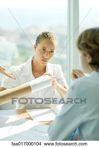 Picture - Woman taking blueprints out of holder. Fotosearch