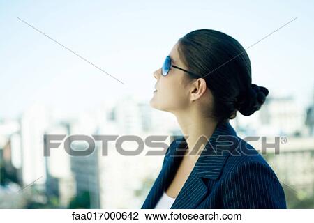 Woman wearing sunglasses, looking up, skyline in background, profile View Large Photo Image Stock Image - Woman wearing sunglasses, looking up, skyline in background, profile. Fotosearch
