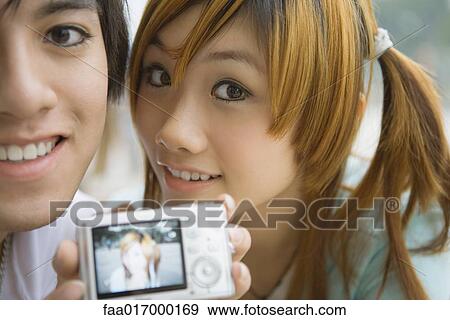 Stock Photo - Young couple holding up digital photo with photo of woman. Fotosearch