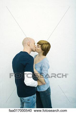 Stock Image - Young couple kissing, side view. Fotosearch