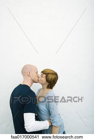 Stock Image - Young couple kissing, side view. Fotosearch